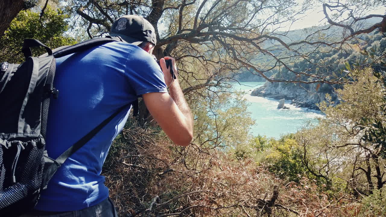 Photorgrapher shooting the Aegean sea coast from a hill with greenery in Greece