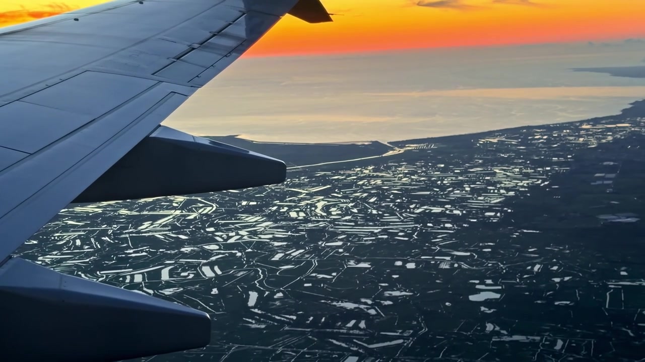 Ein Flugzeugflügel gleitet während des Sonnenuntergangs über eine spiegelnde Landschaft und fängt den ruhigen Farbübergang ein. Ideal für Reise- oder Luftfahrtthemen