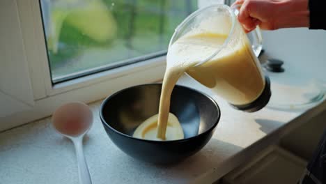 blended pancake mix flows smoothly into bowl during sunny home breakfast prep