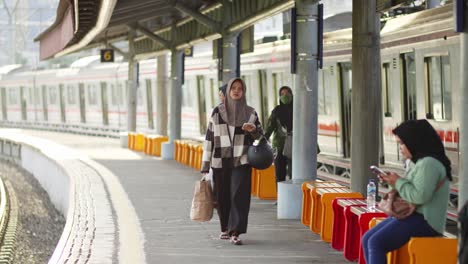 people walking on the platform at kampung bandan station with a train in the background