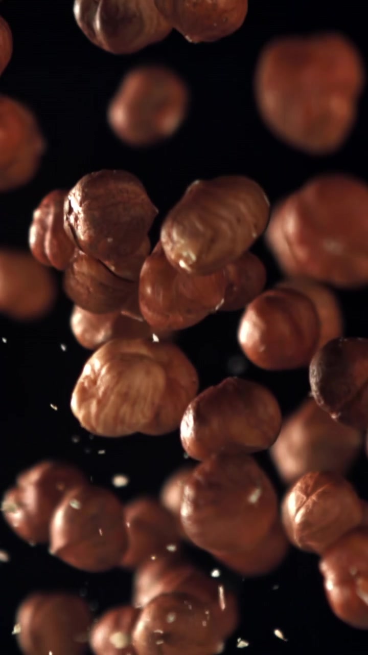 Nocciole pelate che cadono al rallentatore su sfondo nero