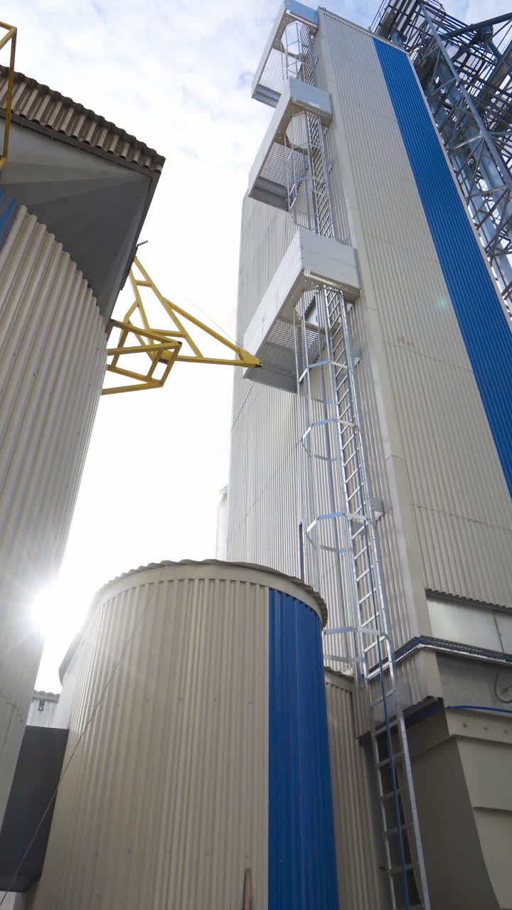 Exterior of a modern factory. Large granary for processing and drying agricultural products. Grain elevator outdoors. Close-up. Vertical video