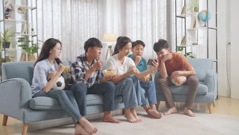 asian teenagers cheering and watching football game on smart phone. team celebrating victory and team disappointed