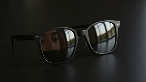 stylish black sunglasses on a dark surface, capturing reflections and showcasing elegant design features in an artistic display of fashion accessories