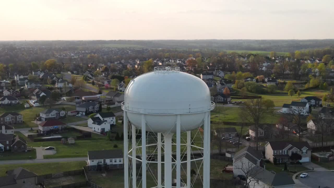 백그라운드에서 교외 이웃을 드러내는 급수탑의 공중 현기증 샷
