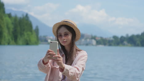 una mujer tomando una selfie junto a un lago.