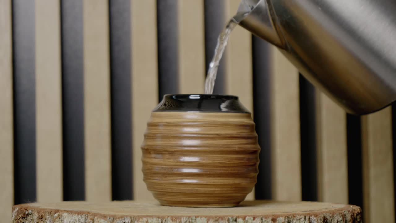 Water from a kettle is poured into the gourd with yerba mate