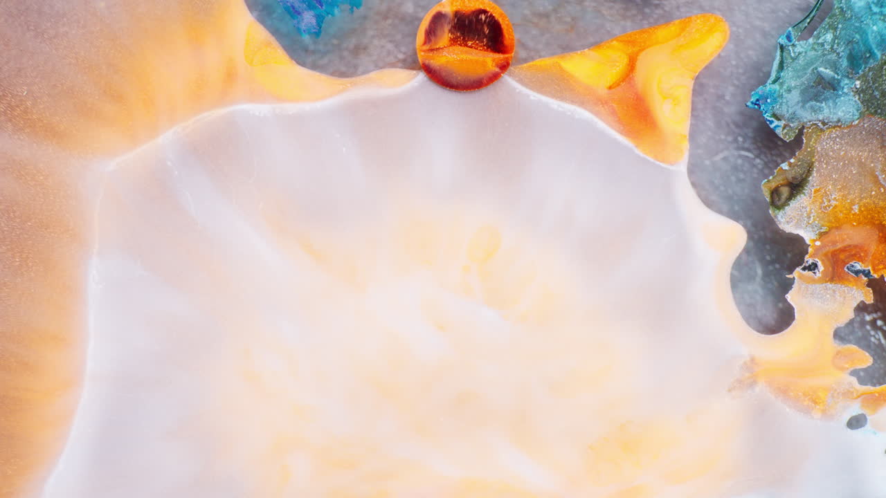 Closeup abstract shot of white ink getting fused with other colored inks and red circular inks