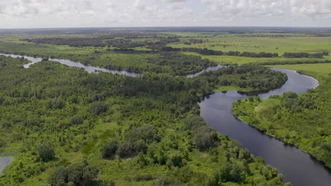 Vista-Aérea-Del-Sinuoso-Río-En-Tierras-De-Cultivo-Que-Conectan-Con-El-Lago-Okeechobee-En-Florida