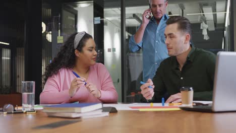 Happy-diverse-business-people-discussing-work-during-meeting-at-office