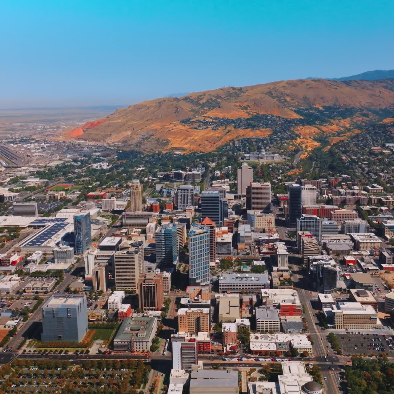 Sunny view of the city with beautiful densely built architecture. Salt Lake City panorama with brown mountains at backdrop