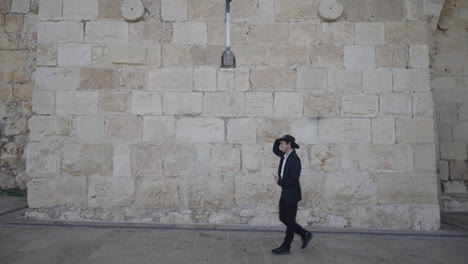 an actor dressed in traditional attire walks along the historic stone walls of jerusalem, capturing a moment of cultural and historical significance in the ancient city