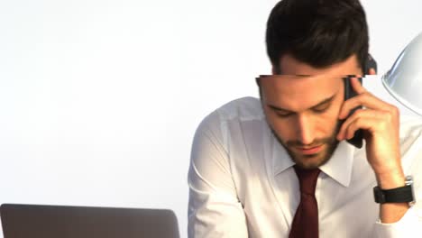 Businessman-working-at-his-desk-and-talking-on-mobile-phone