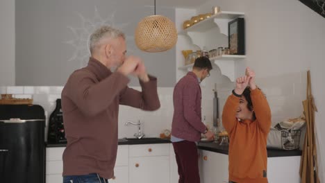 gay man teaches son dancing while partner prepares breakfast