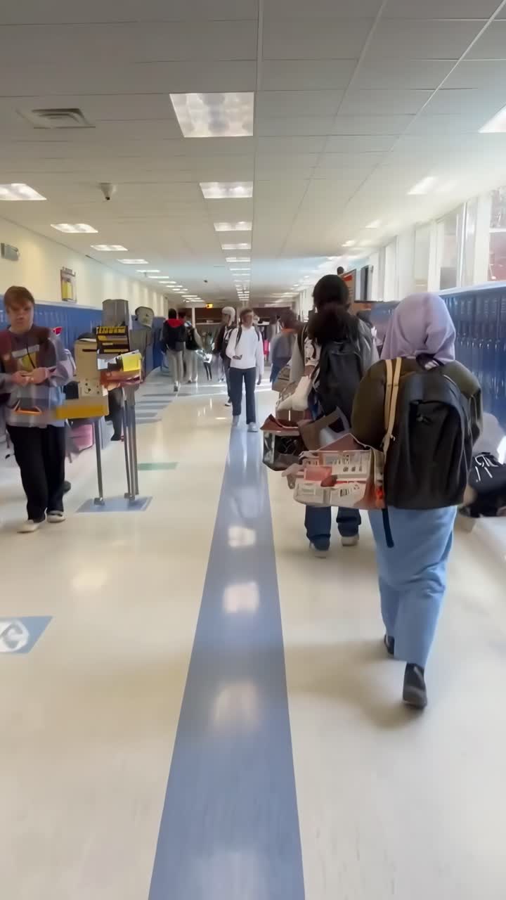 Video merekam lorong sekolah yang ramai dari sudut pandang menengah, menampilkan beragam siswa