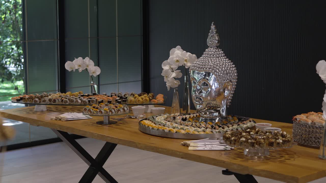 luxury sushi buffet table with metallic buddha head centerpiece and elegant floral decor