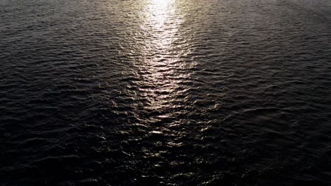 Weitwinkelaufnahme-Aus-Der-Luft-Auf-Das-Dunkle-Wasser-Des-Karibischen-Ozeans,-Während-Die-Drohne-Zur-Untergehenden-Sonne-Fliegt