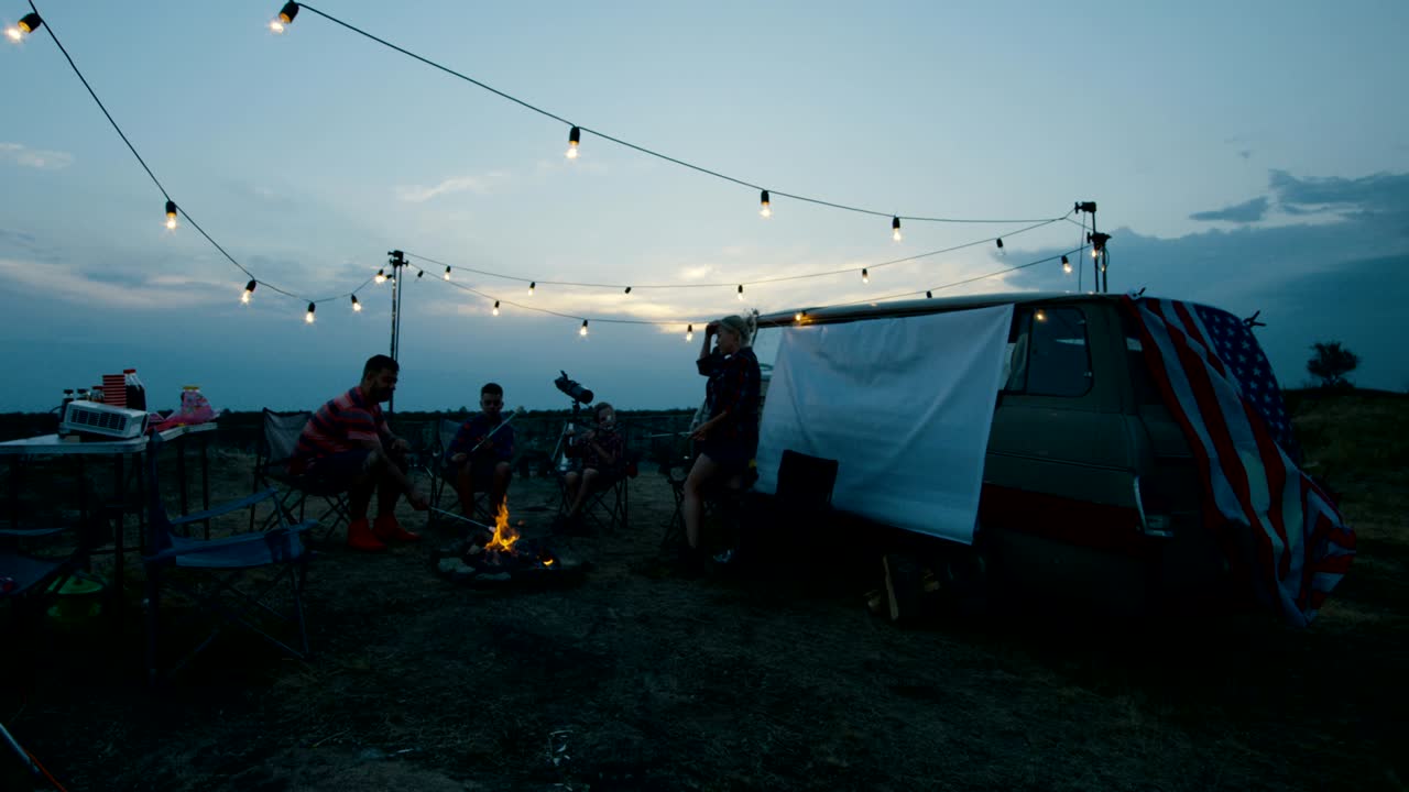 Laughing family frying marshmellow on bonfire