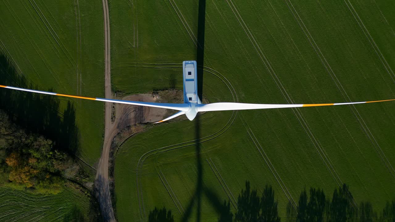 Wind turbine standing in green field next to german autobahn highway, generating renewable clean green eco friendly energy. speed ramp hyper motion time lapse Lovely aerial view fly reverse drone