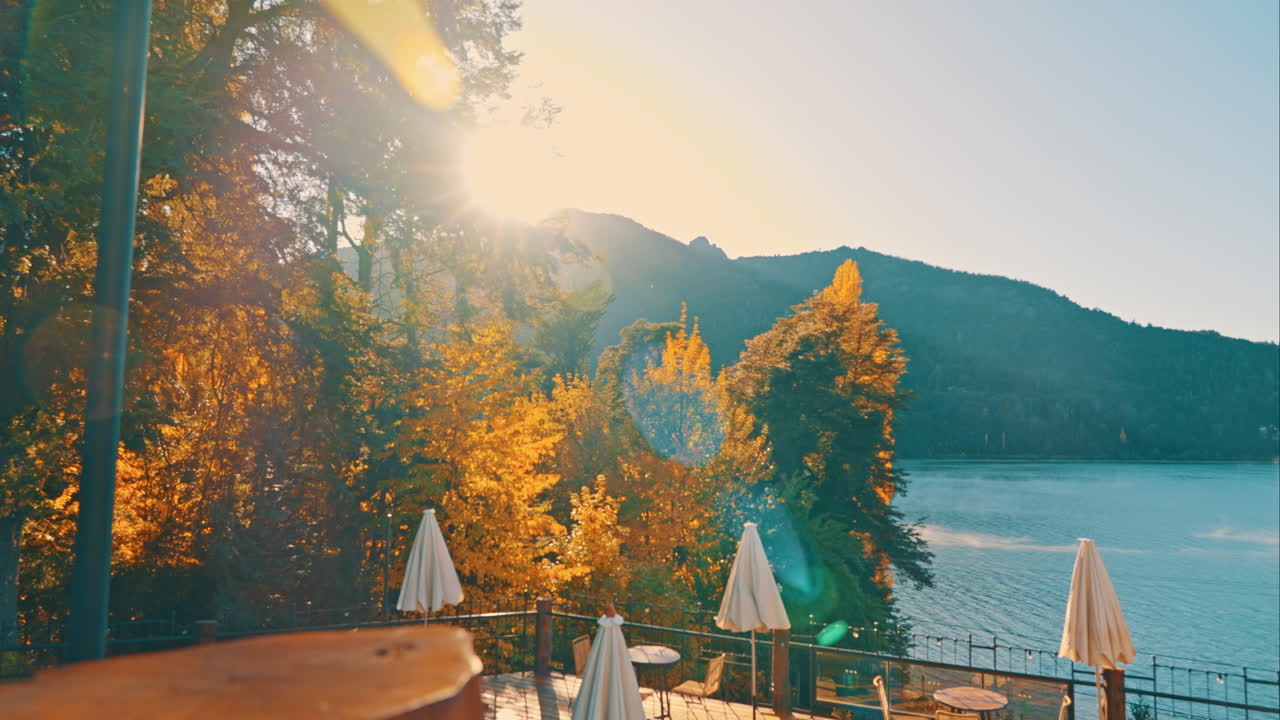 紅葉した木々とテラス、そして山間の湖に昇る黄金の日の出