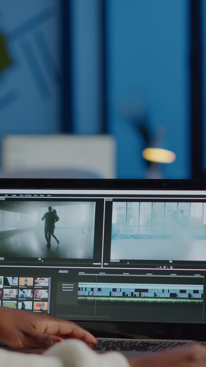 Vertical video African videographer working at laptop from office editing video project