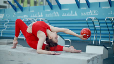 acrobatic woman with ball in red leotard