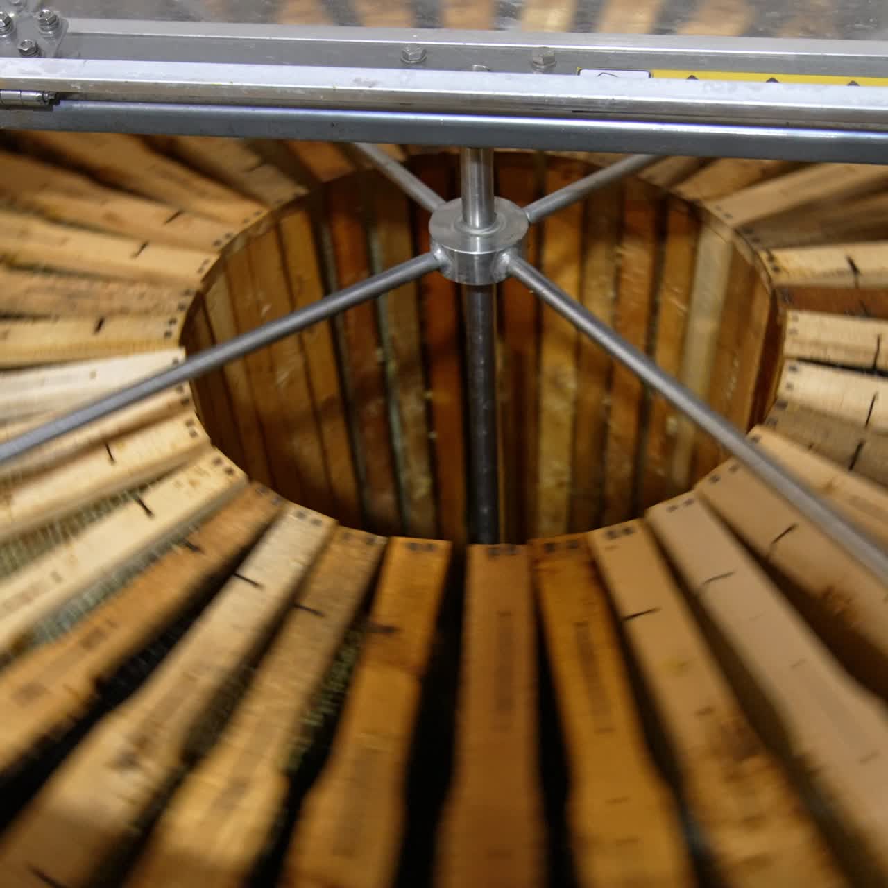 Electric metal barrel machine loaded with wooden frames. The equipment starts to rotate for getting fresh honey from honeycombs