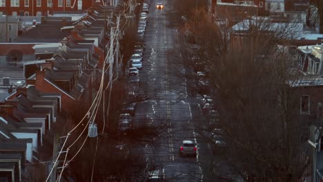 Aerial-long-zoom-of-urban-city-street-with-barren-trees-during-winter-dusk