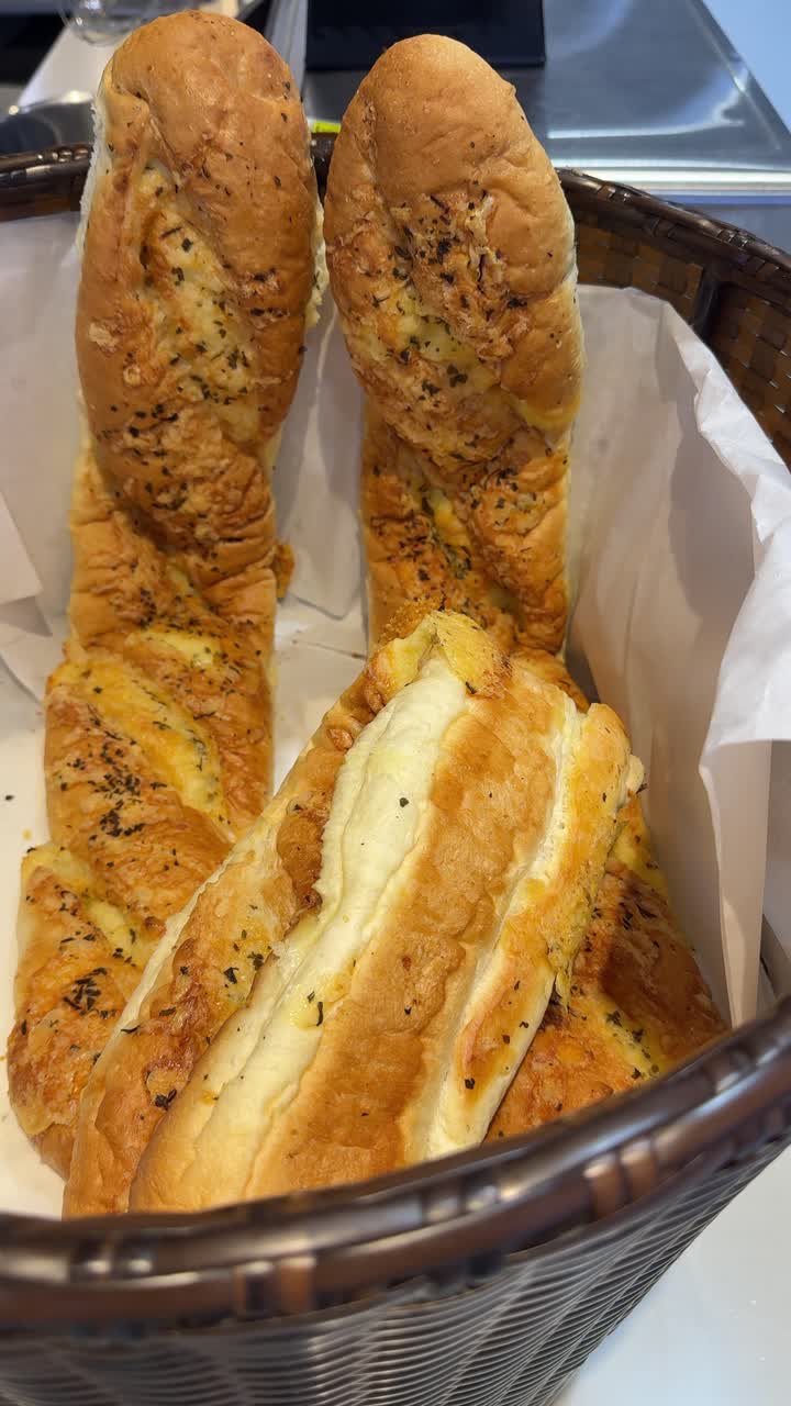 Pagnotte di pane fresco all'aglio e formaggio in un cesto intrecciato