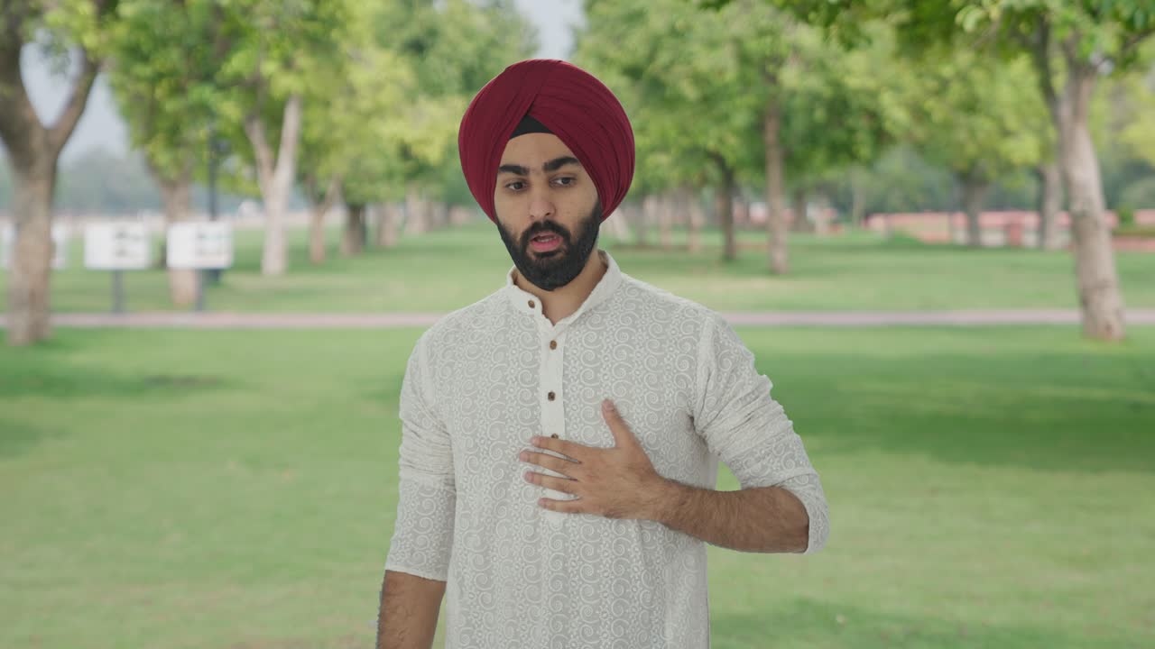 Uomo indiano Sikh malato che ha un attacco d'asma nel parco