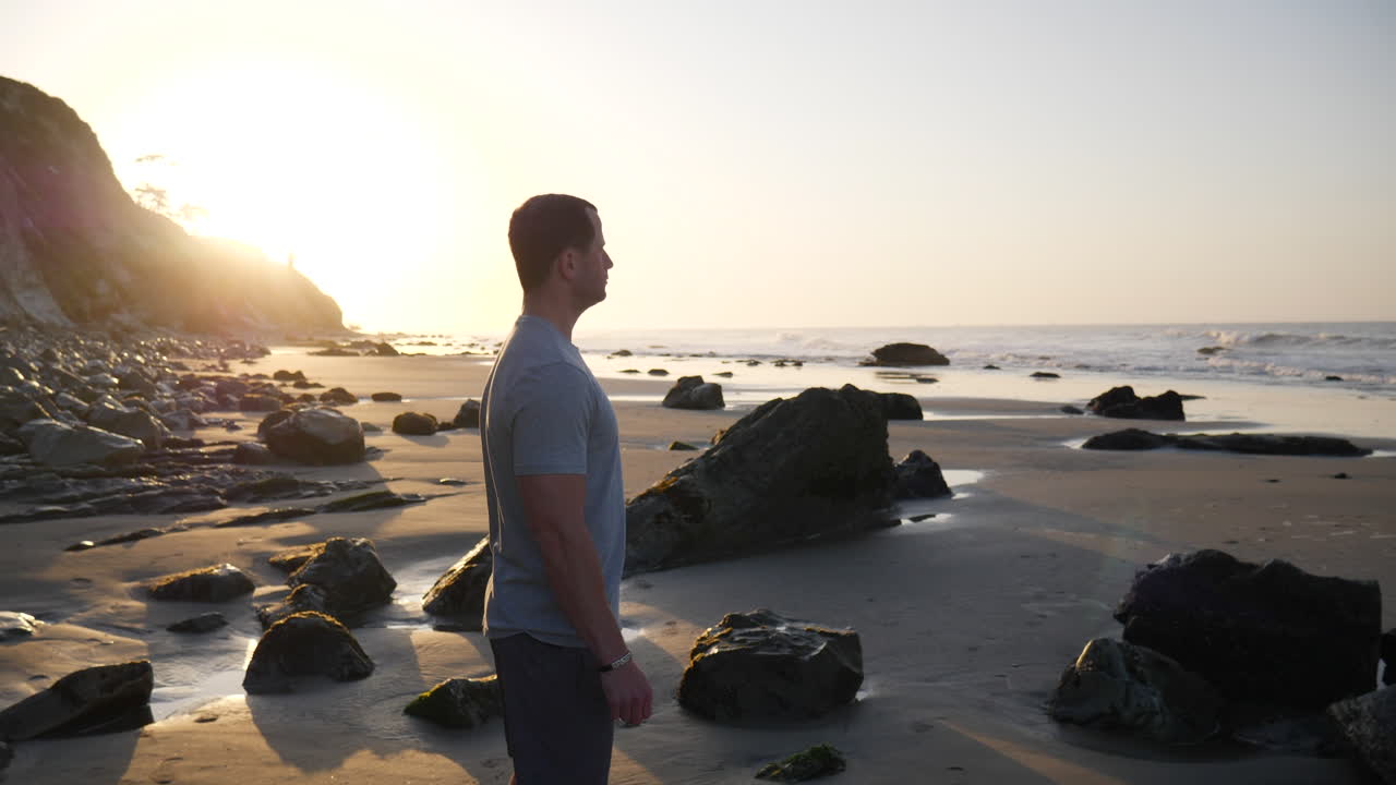 un hombre fuerte preparándose para correr por la mañana y hacer ejercicio físico en la playa al amanecer en santa bárbara, california