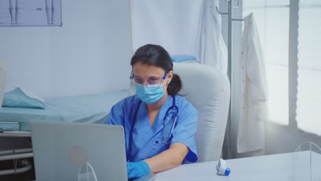 enfermera escribiendo en una computadora portátil con guantes médicos