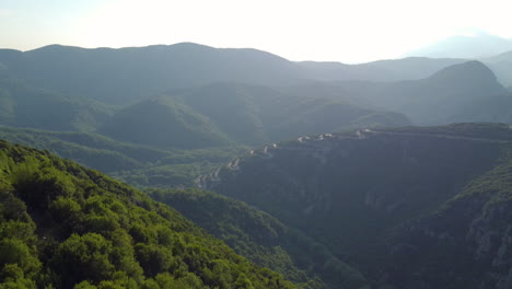 a distant aerial view captures the serpentine narrow road leading to vikos gorge in northern greece, a route filled with twists and turns sharply winding up the mountain in the zagori region