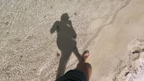 Man-walking-on-clean-blue-flag-beach-in-Halkidiki-Peninsula,-Greece