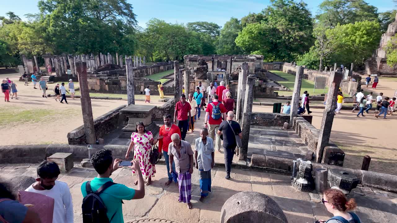 Visitors enjoying the ancient Hatadage shrine in the historic city of Polonnaruwa, Sri Lanka, showcasing cultural and architectural heritage amidst lush greenery.
