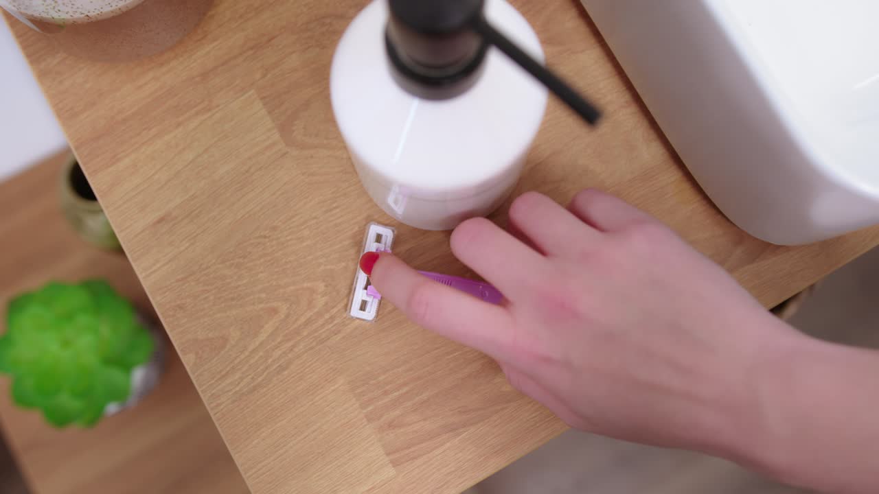 Overhead View Of A Woman's Hand Getting A Pink Disposable Blade Shaver