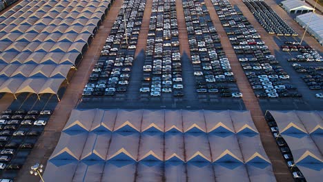 rows of completed vehicles parked at assembly plant in aerial view
