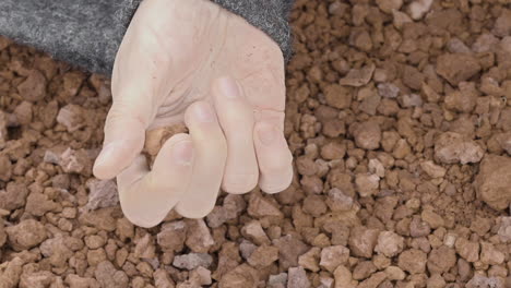 Close-up-of-a-woman's-hand-sensually-playing-with-volcanic-gravel