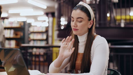 mujer relajándose con una computadora portátil en la biblioteca