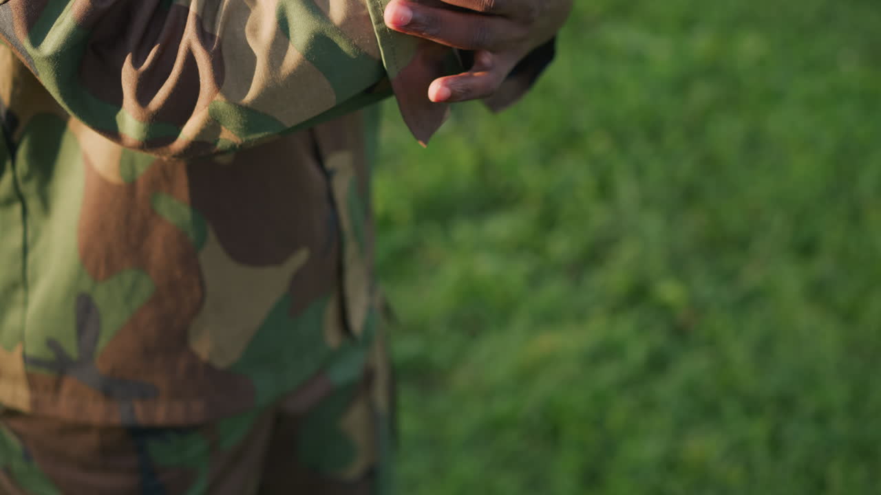 Una guardia sistema l'uniforme sul campo di addestramento, un soldato attento prepara l'uniforme e ispeziona attentamente il camuffamento, una guardia militare sistema l'uniforme e controlla il camuffamento prima dell'inizio della pattuglia