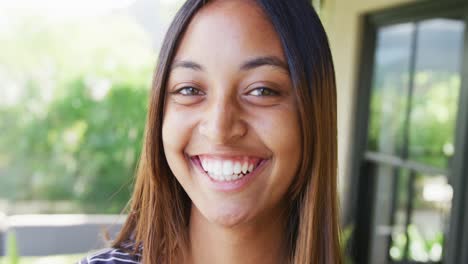 Portrait-of-a-happy-biracial-teenager-girl-at-home,-slow-motion