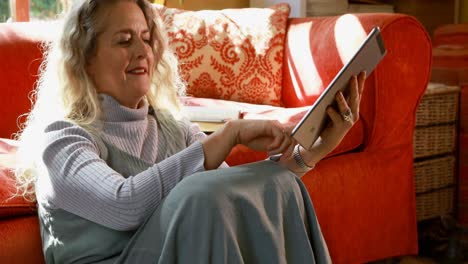 mature woman using digital tablet in living room 4k