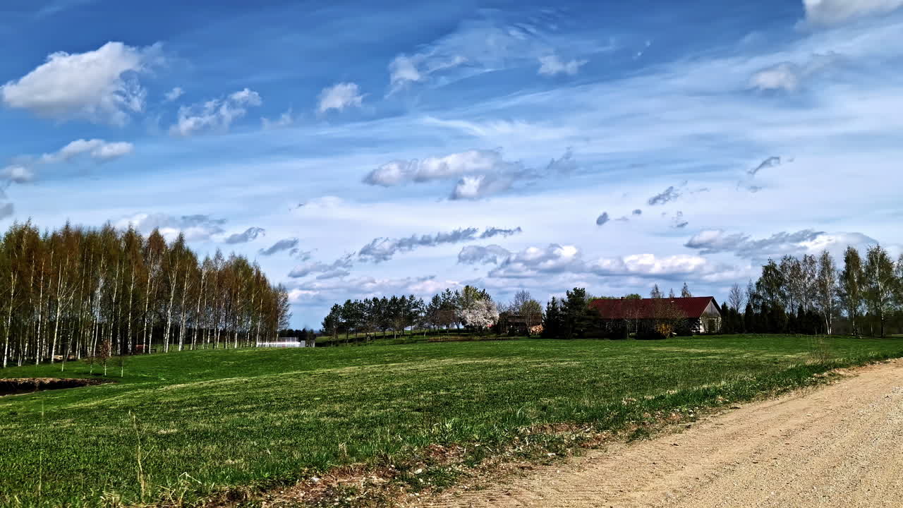 Countryside view with pond, trees, fields, and distant houses under sky