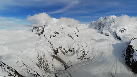 Drohnenflug-über-Die-Schweizer-Alpen,-Mit-Blauem-Himmel-Und-Jetzt-Bedeckten-Bergen