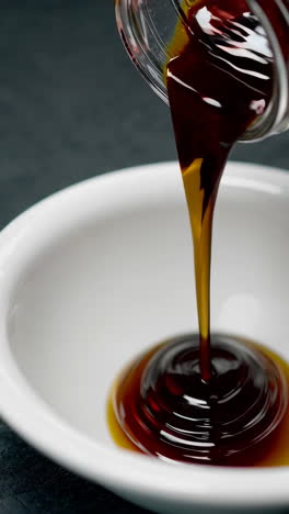 pouring a dark brown sauce into a bowl