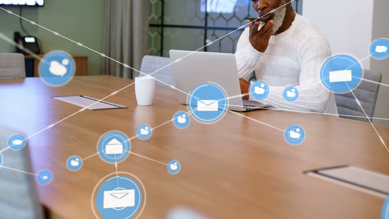 Uomo anziano che parla al telefono e digita sul laptop, con una mail aziendale fluttuante che avvia una rete di icone che lo oscura.