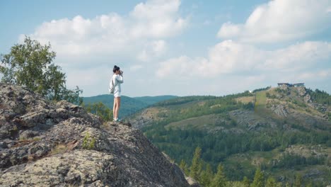 woman hiking and taking pictures of a mountain view