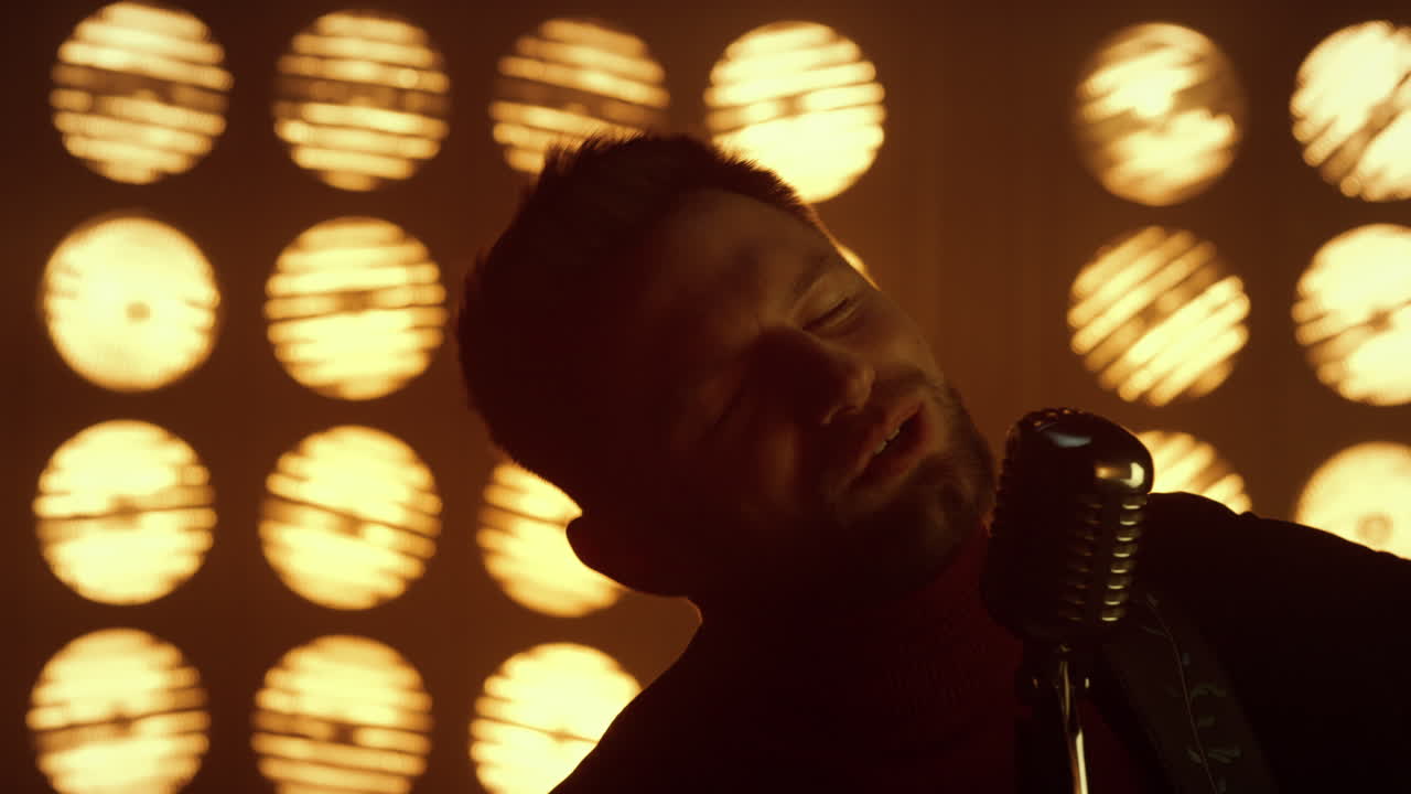Fiery showman singing song in microphone close up. Man enjoying performance.