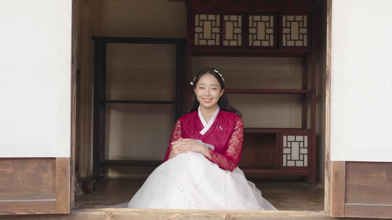 Smilende ung kvinnelig modell i Hanbok i et tradisjonelt koreansk hus