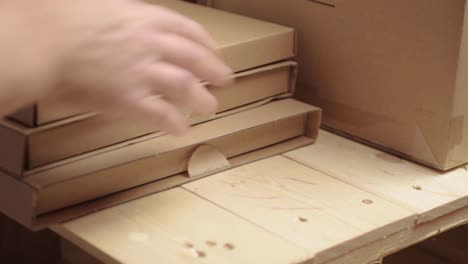 Hand-moving-cardboard-boxes-on-a-wooden-pallet